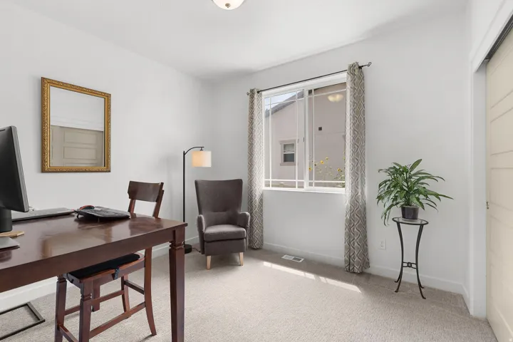 Recessed lighting illuminates the neutral-toned carpet and white walls