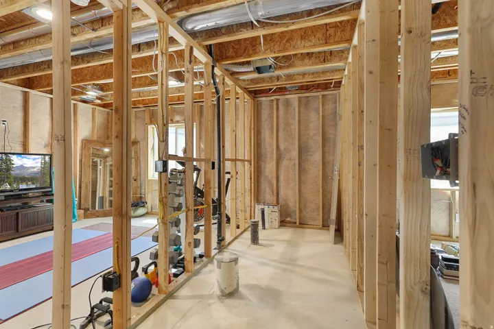 Unfinished lower level with wood framing, exposed ceiling joists, concrete flooring, and an egress window