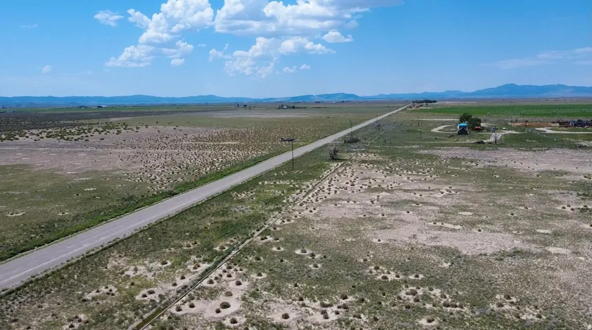 Expansive, undeveloped parcel featuring an asphalt road and distant mountain ranges