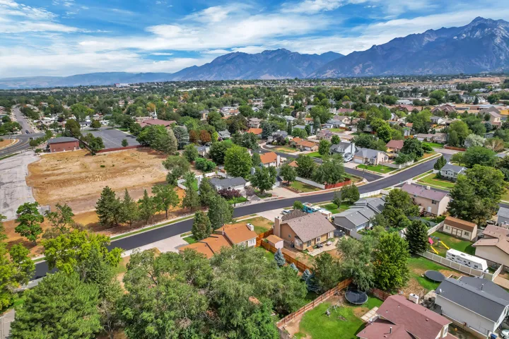 Expansive suburban setting with established residential properties, mature trees, paved streets, and distant mountain backdrops