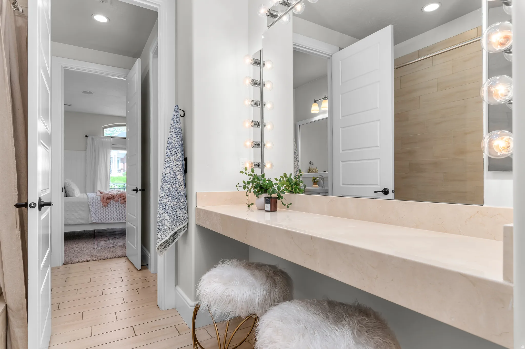 Built-in vanity with a stone countertop, Hollywood-style lighting, and a large mirror