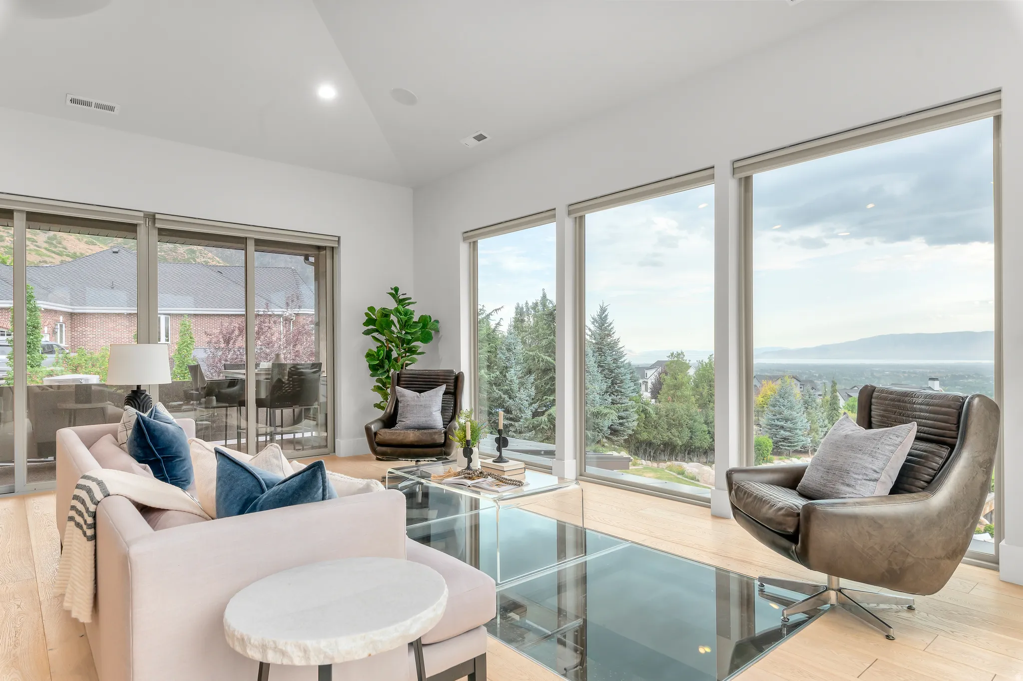 Spacious living area featuring expansive windows, wood-finish flooring, a glass floor insert, recessed lighting, and a sliding glass door
