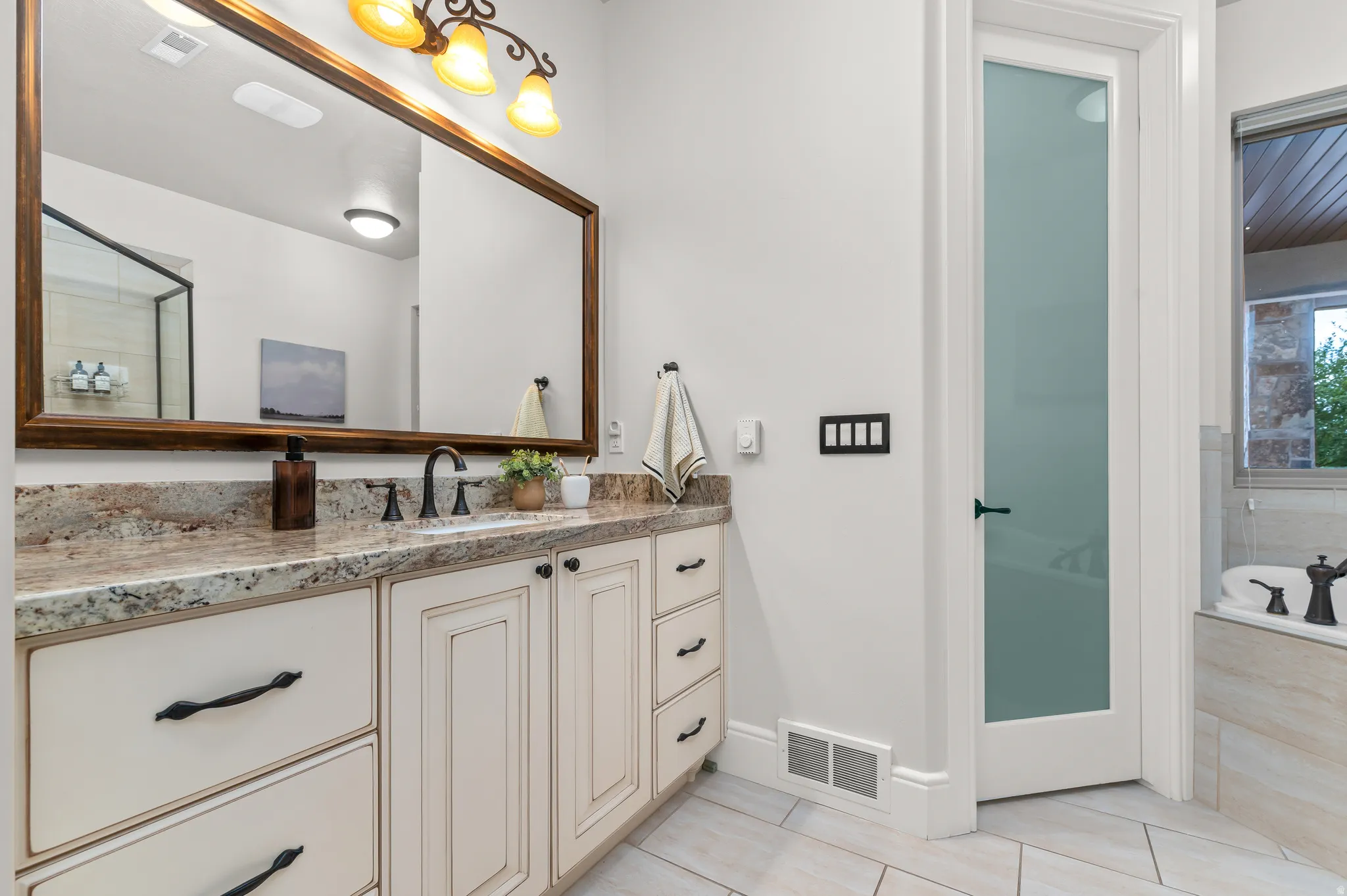 Double vanity with a granite countertop, undermount sink, and dark bronze fixtures