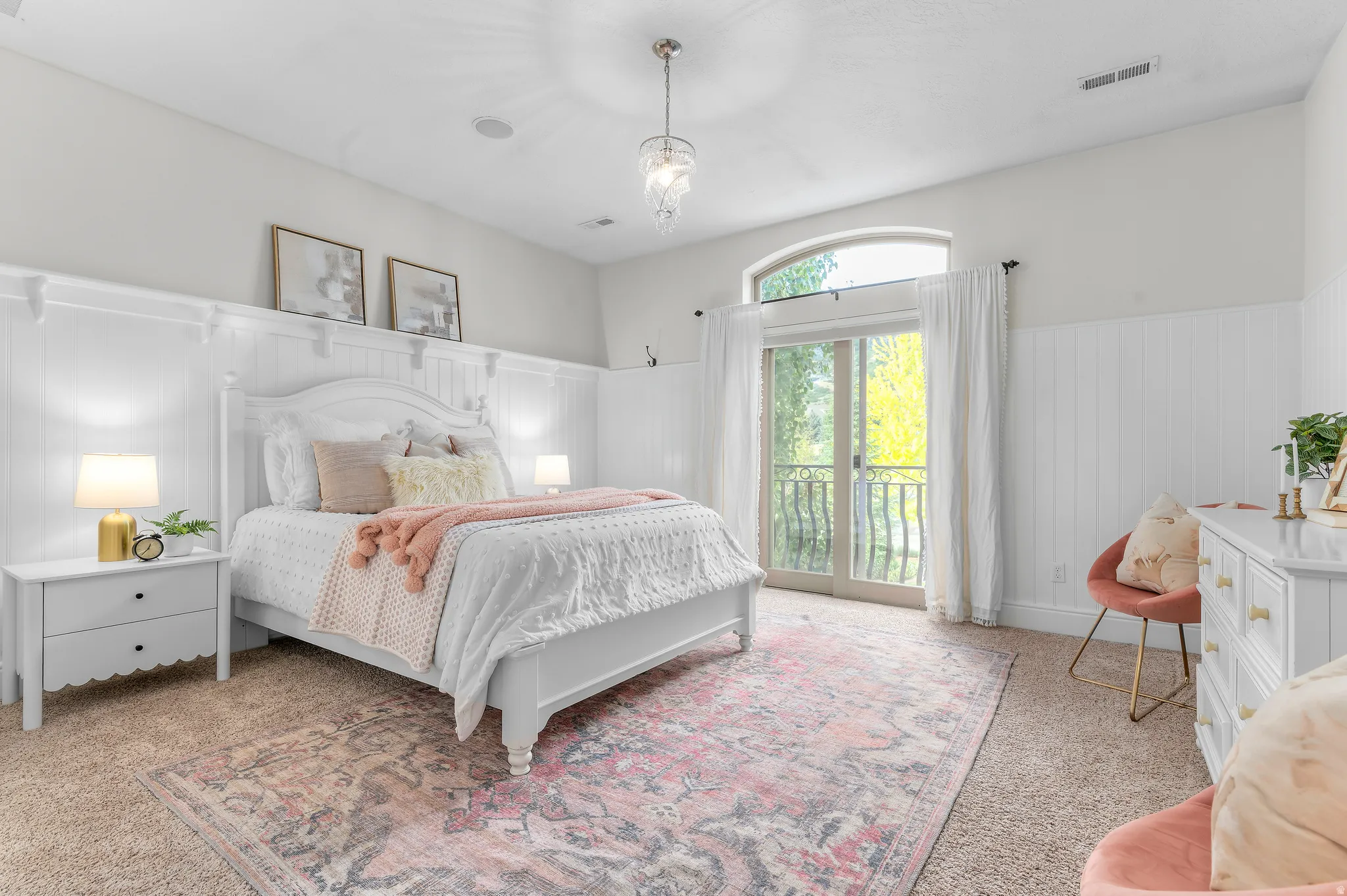Board and batten wall detailing, arched transom window, glass sliding doors, private balcony with wrought iron railing, and a decorative ceiling light fixture