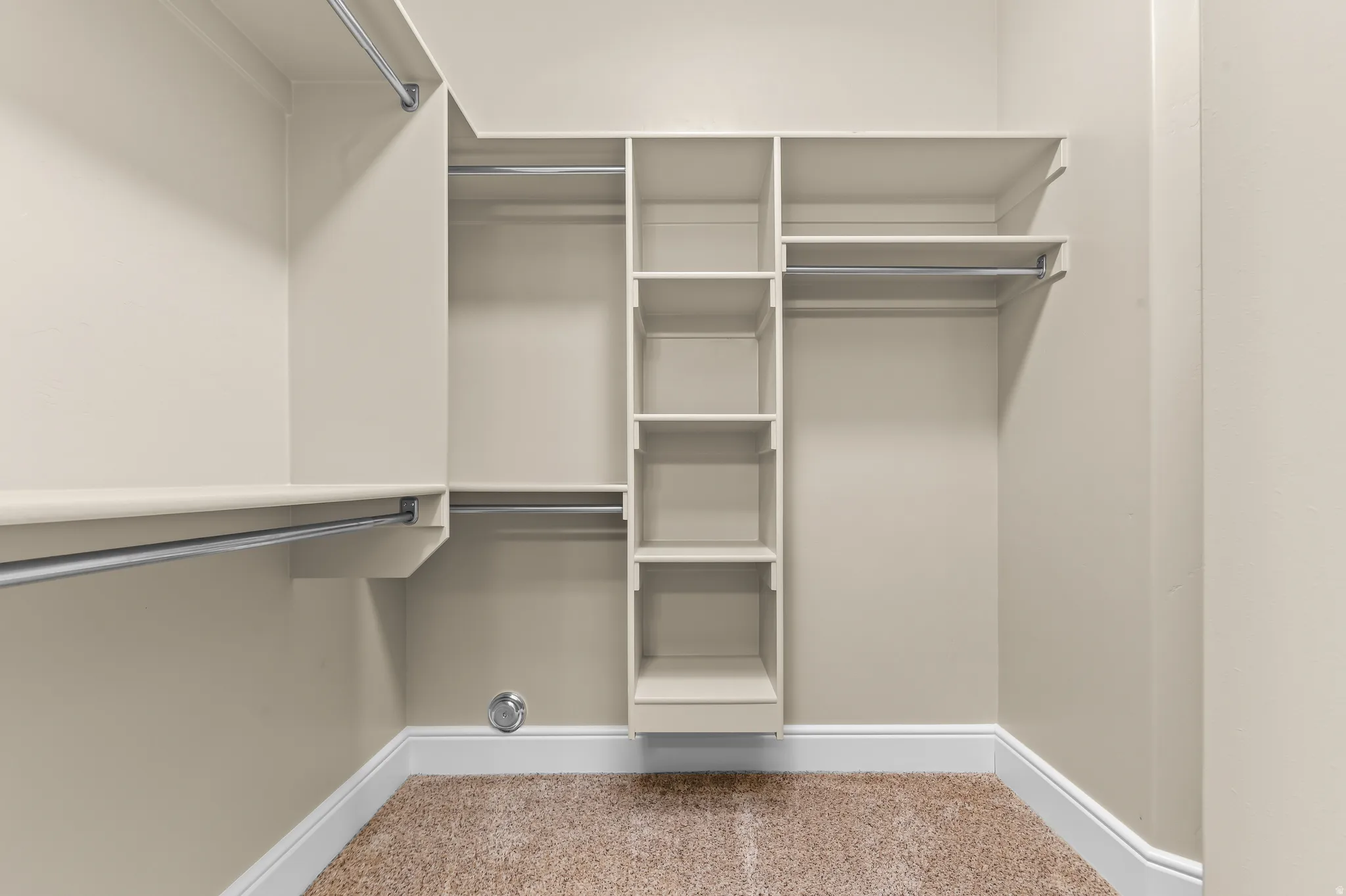 Built-in shelving, multiple hanging rods, and light-toned walls