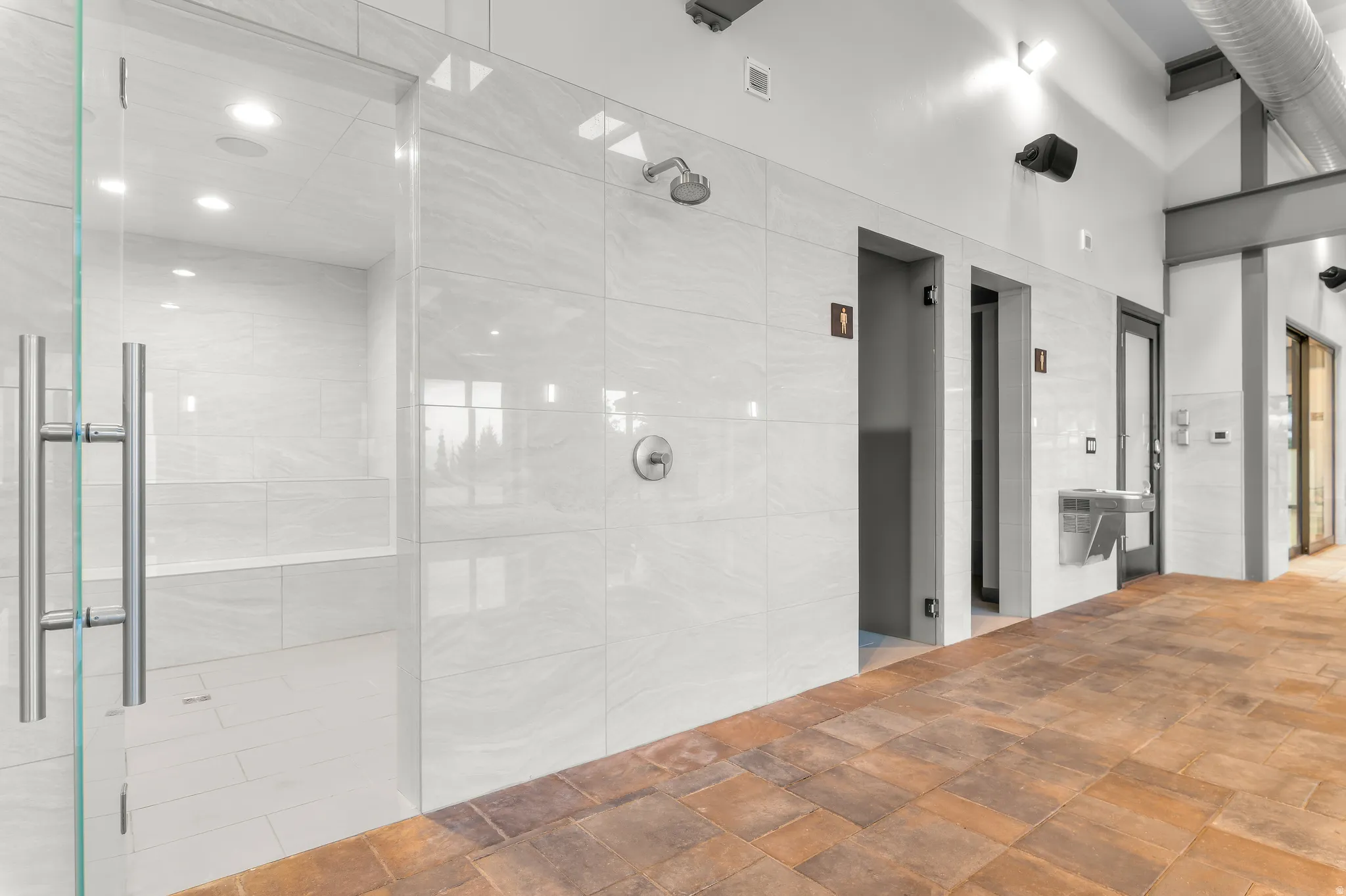 Shower facility featuring full tile enclosure, glass door, and built-in bench