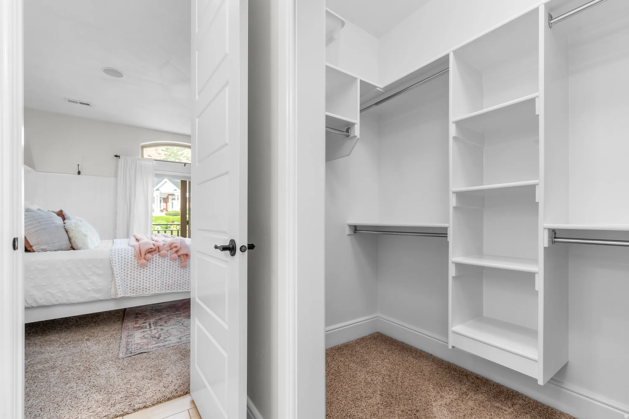 Walk-in closet with built-in shelving, multiple hanging rods, and carpet flooring