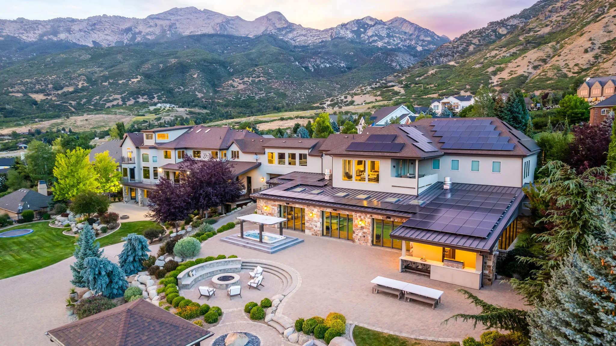 Expansive exterior with multi-level hardscaping, a built-in fire pit, covered outdoor kitchen, and a separate gazebo