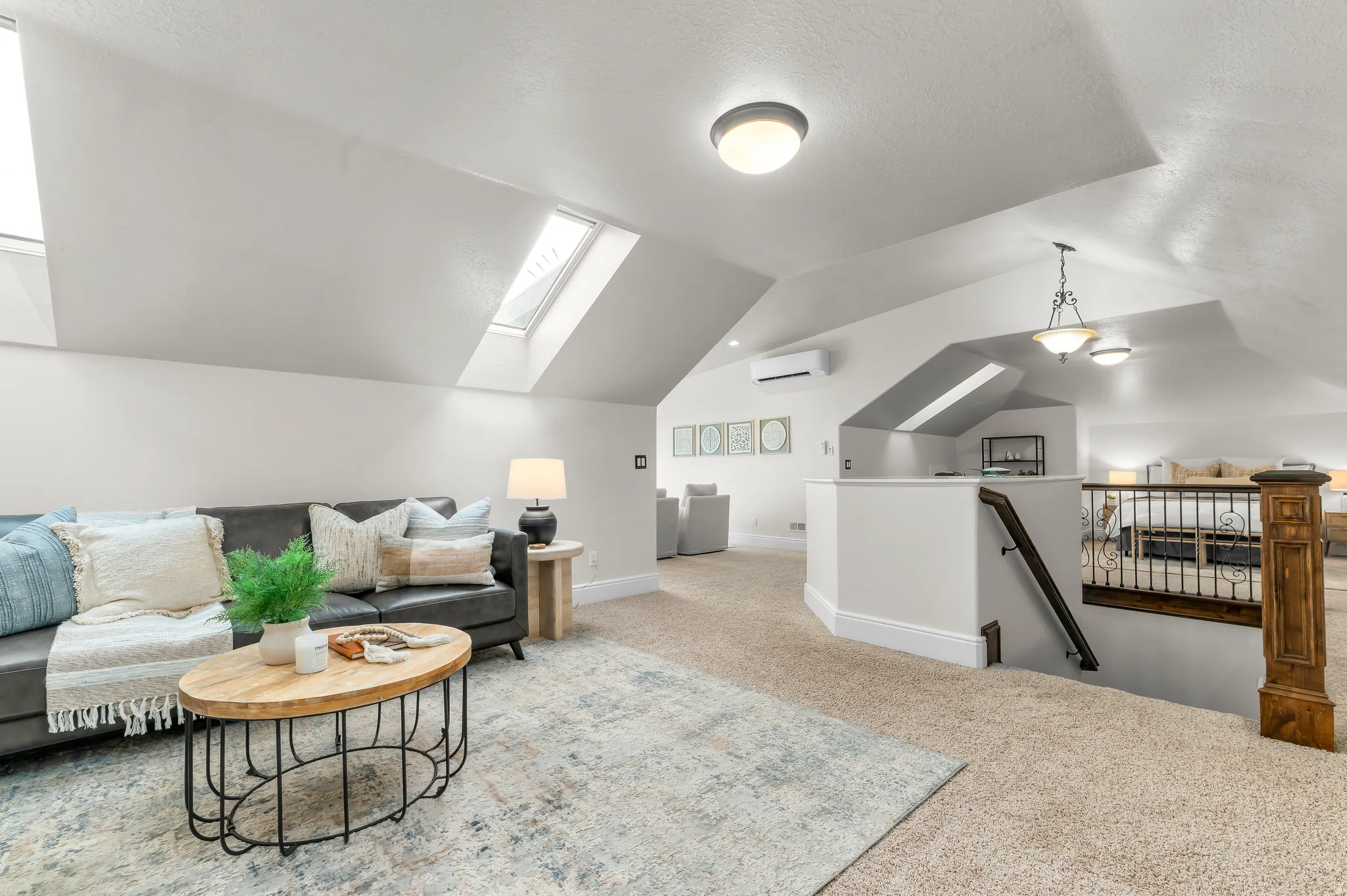 Vaulted ceilings with multiple skylights, recessed lighting, carpeted flooring, and a detailed wood and metal stair railing