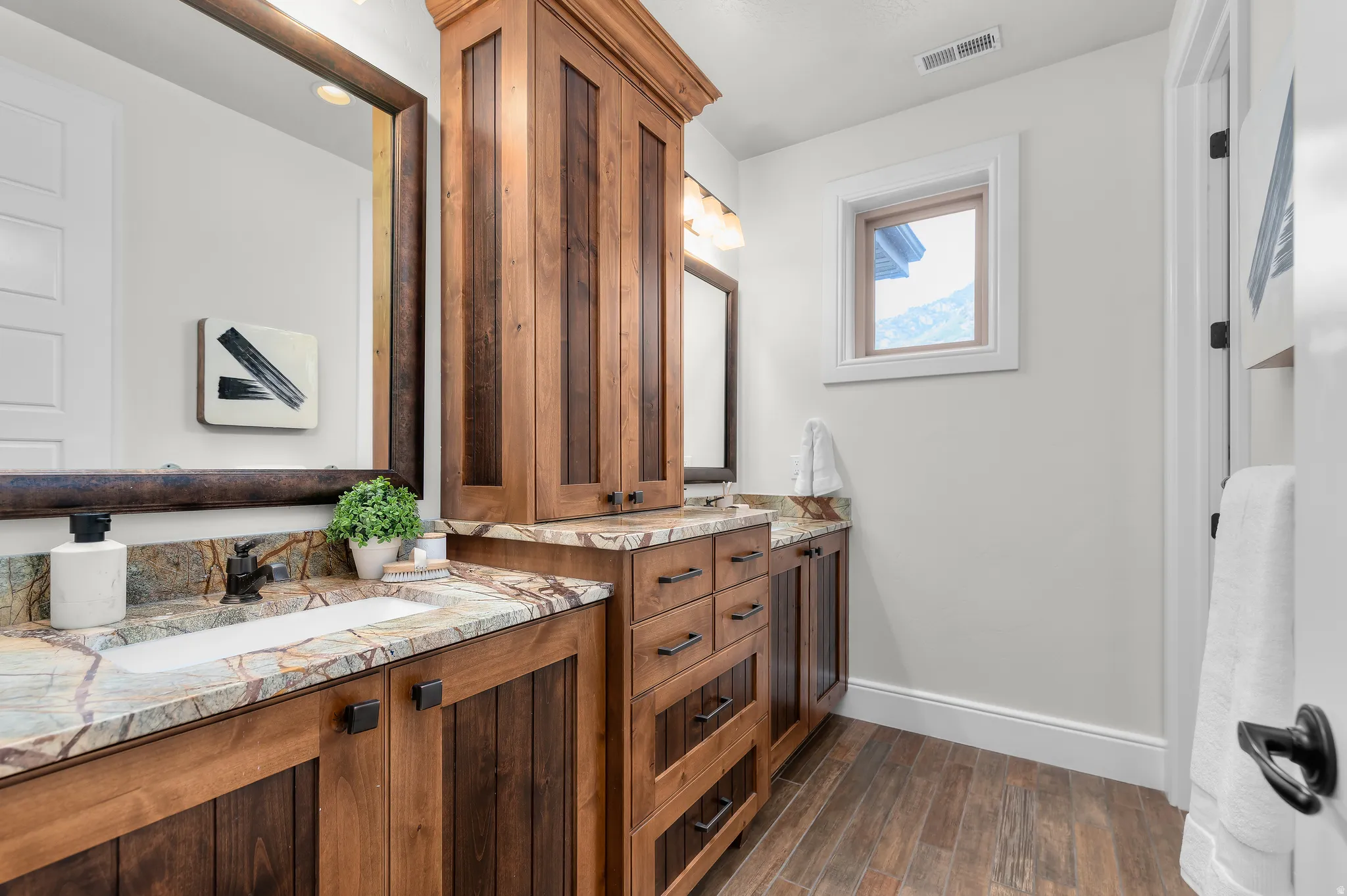 Dual wood-finish vanities with undermount sinks and stone countertops