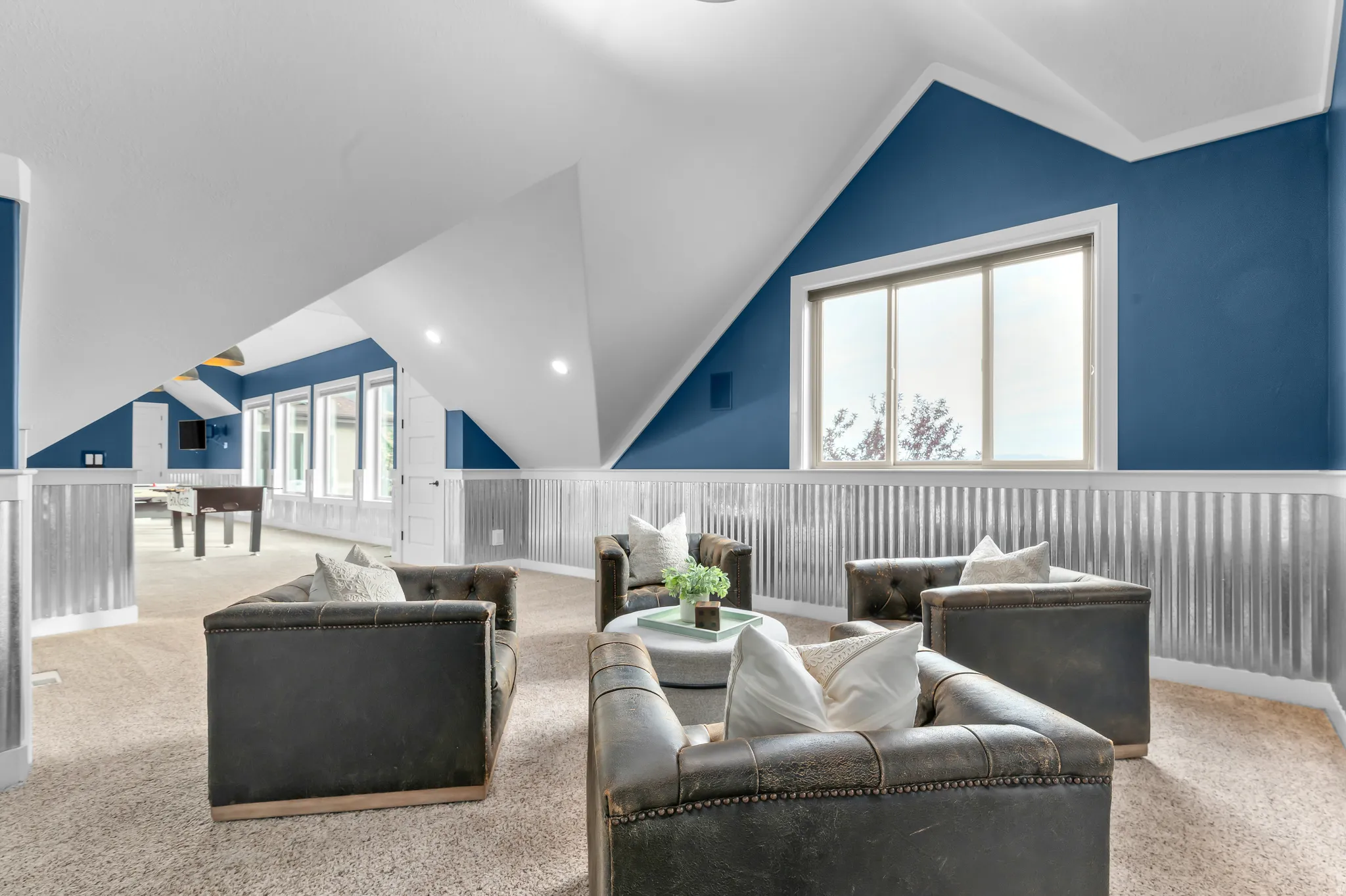 Spacious bonus room featuring sloped ceilings, recessed lighting, multiple windows, and corrugated metal wainscoting
