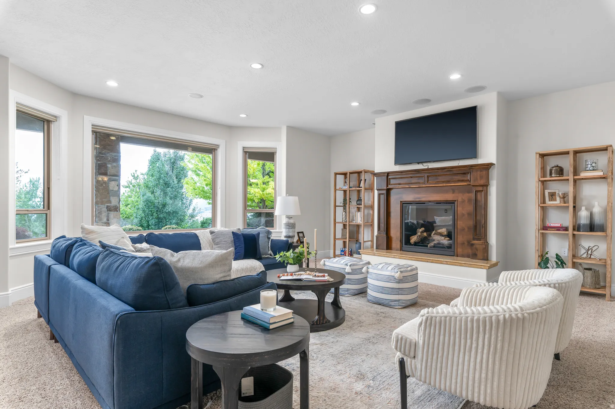 Built-in fireplace with a wood mantle, recessed lighting, large windows, and built-in shelving