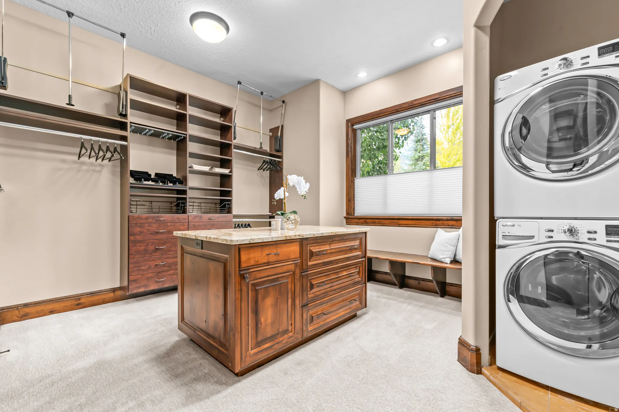 Custom closet with built-in shelving, center island with stone countertop, and integrated laundry appliances