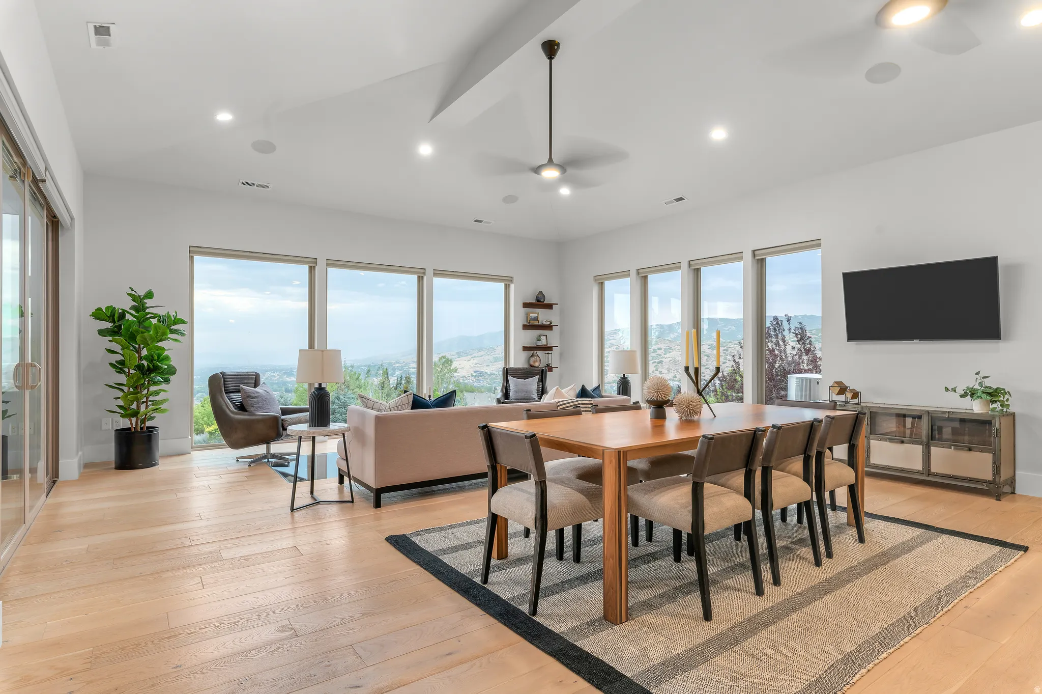 Expansive living area with light wood-finish flooring, recessed lighting, and large windows