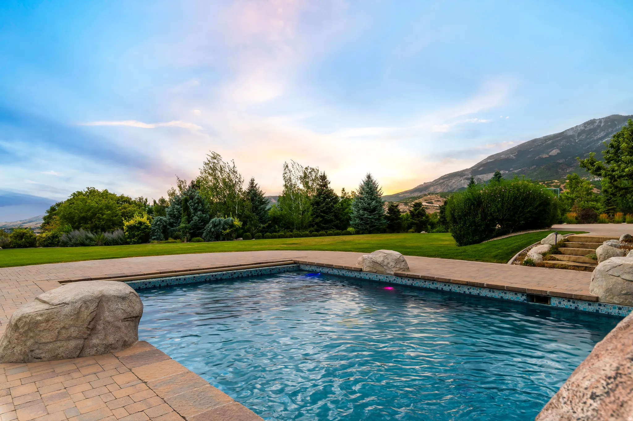 Swimming pool with a patterned tile perimeter and brick paver decking
