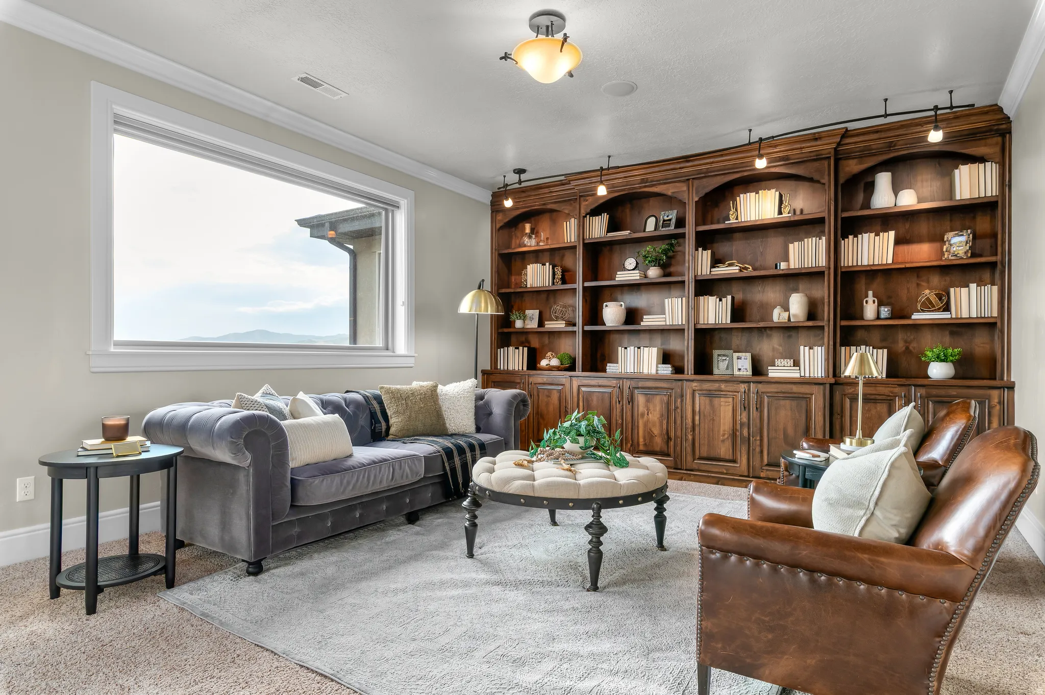 Built-in wood shelving with integrated lighting, large window, crown molding, and carpeted flooring