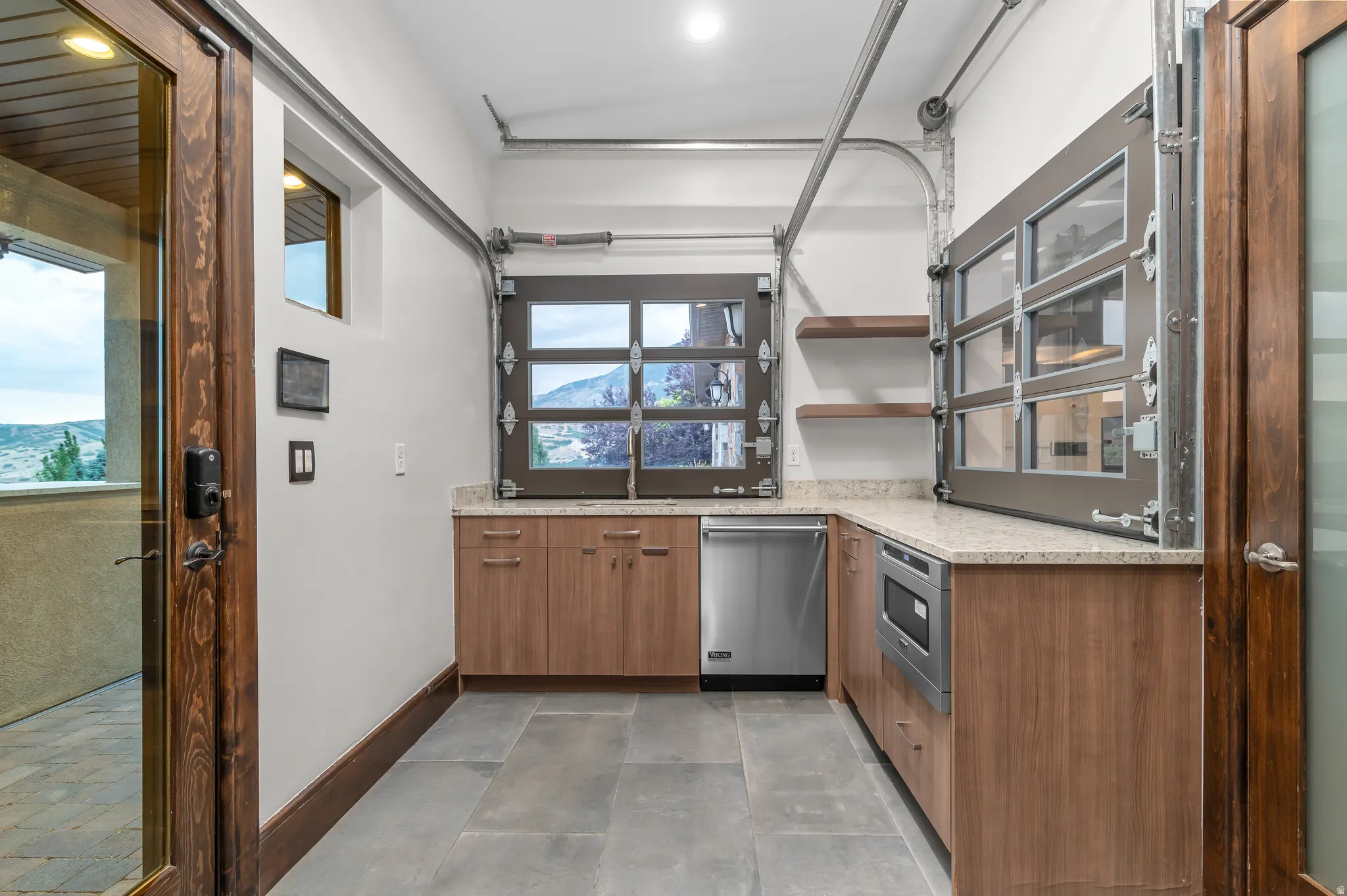Built-in cabinetry, stainless steel dishwasher, integrated microwave, wood-finish flooring, and light-toned countertops