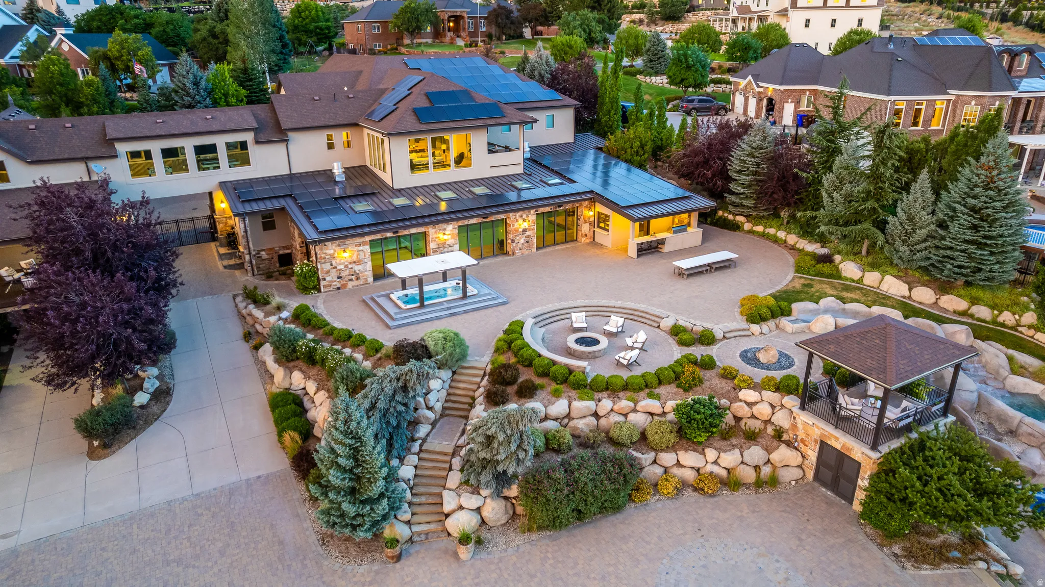 Expansive multi-level hardscaping with integrated fire pit, outdoor kitchen, and stone retaining walls