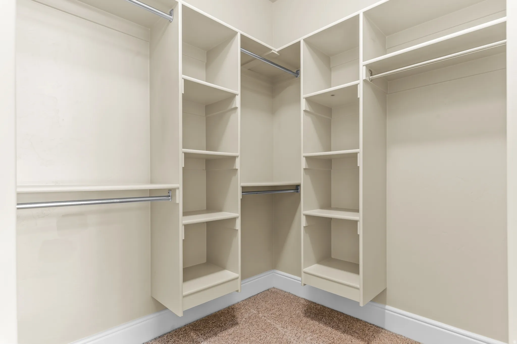 Walk-in closet featuring built-in shelving, multiple hanging rods, and carpet flooring