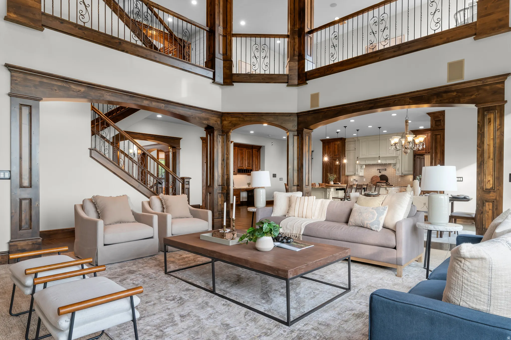 Two-story living area with wood-finish flooring, exposed wood beams, and a wrought iron staircase