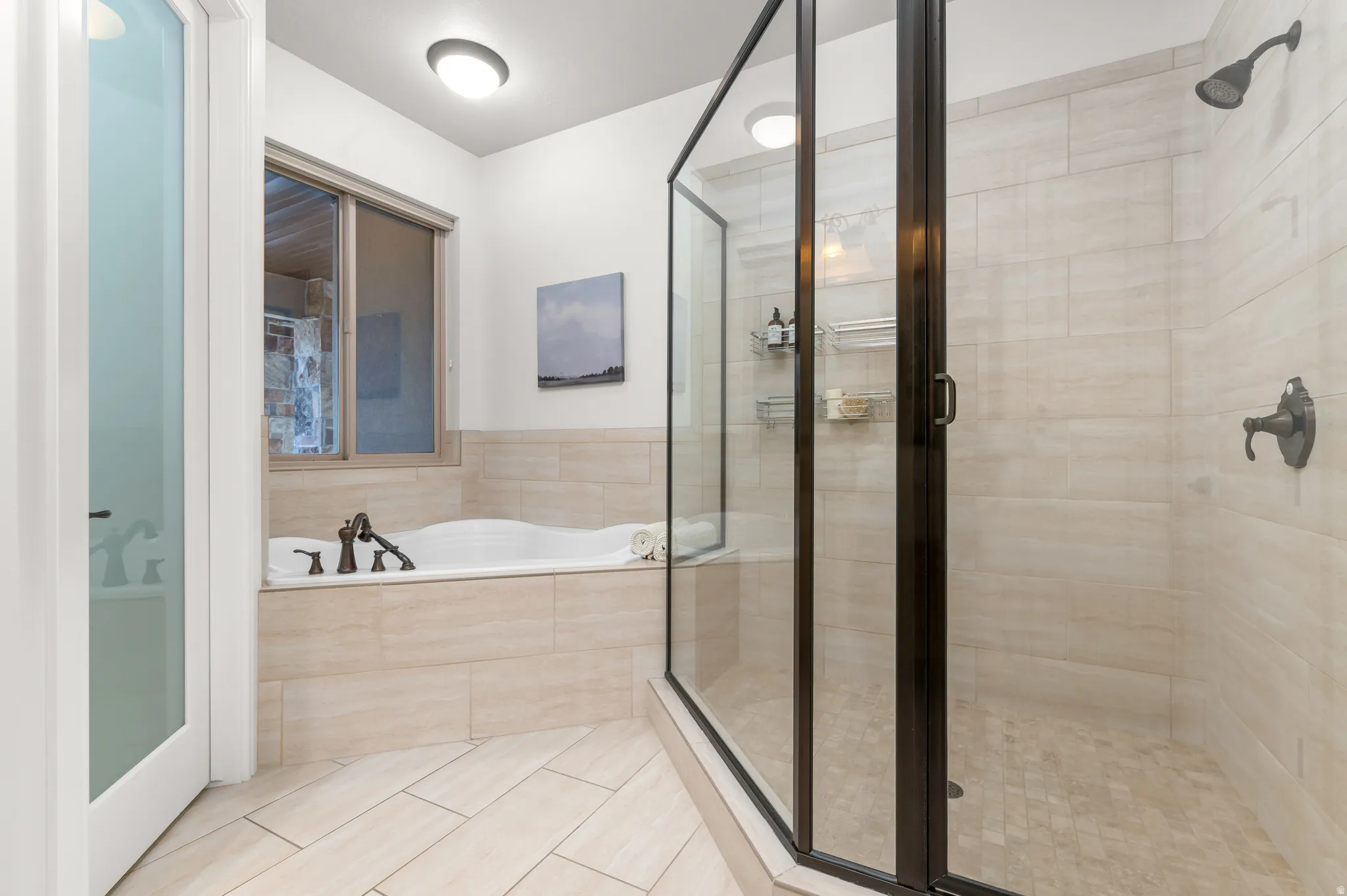 Walk-in shower with dark bronze framing, an integrated soaking tub, and neutral-toned wall and floor tile