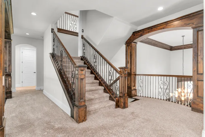 Staircase featuring wood-finish newel posts and railings with wrought iron balusters