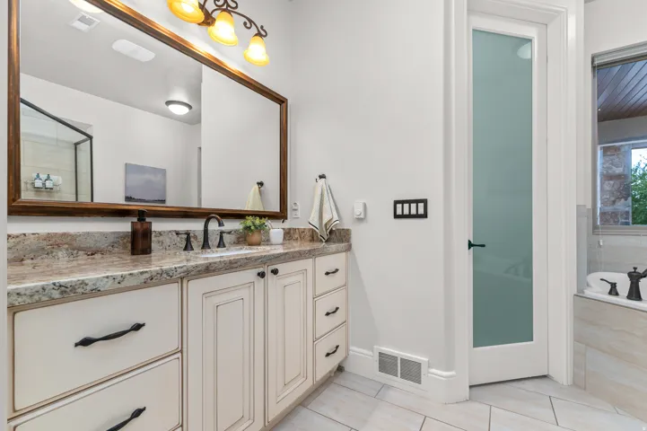 Double vanity with a granite countertop, undermount sink, and dark bronze fixtures