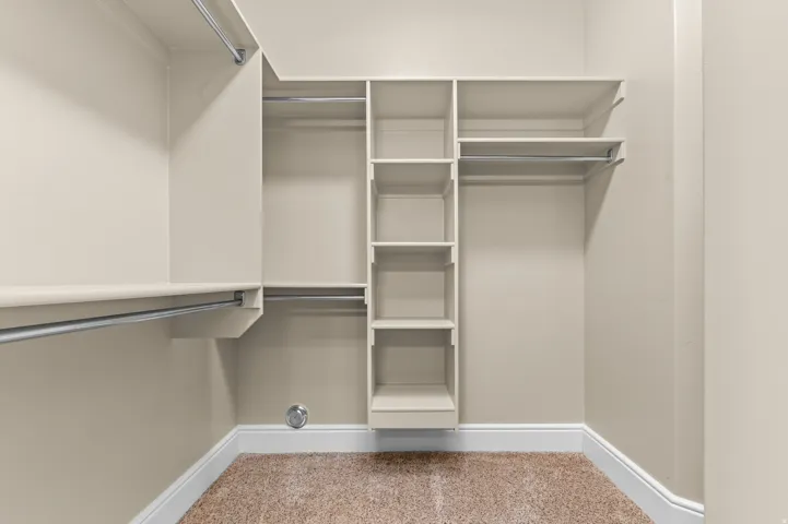Built-in shelving, multiple hanging rods, and light-toned walls