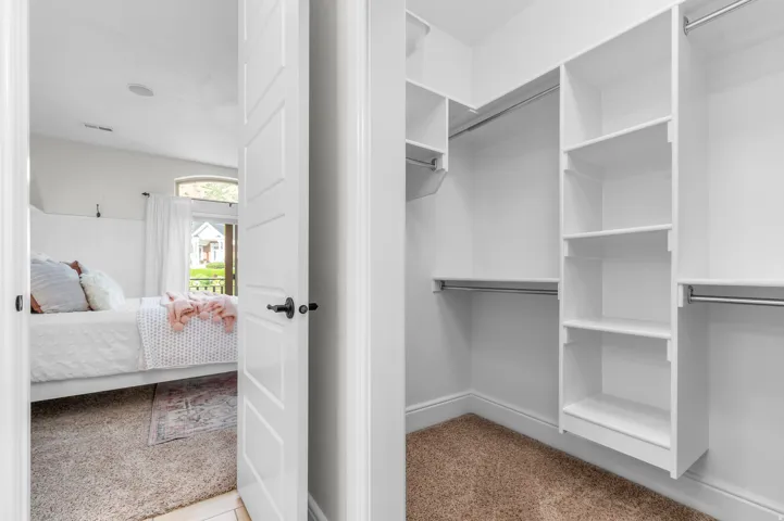 Walk-in closet with built-in shelving, multiple hanging rods, and carpet flooring