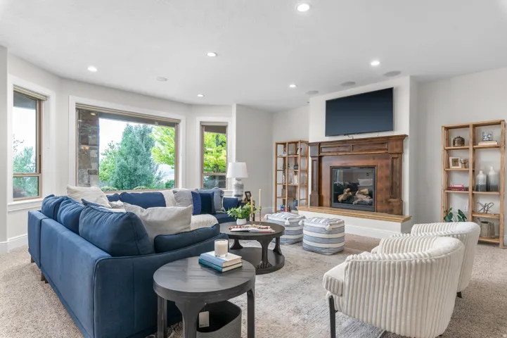Built-in fireplace with a wood mantle, recessed lighting, large windows, and built-in shelving