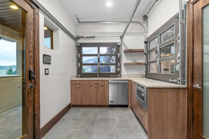 Built-in cabinetry, stainless steel dishwasher, integrated microwave, wood-finish flooring, and light-toned countertops