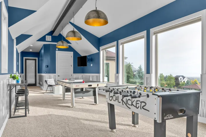 Expansive bonus room featuring multiple large windows, vaulted ceilings with accent beams, and recessed lighting