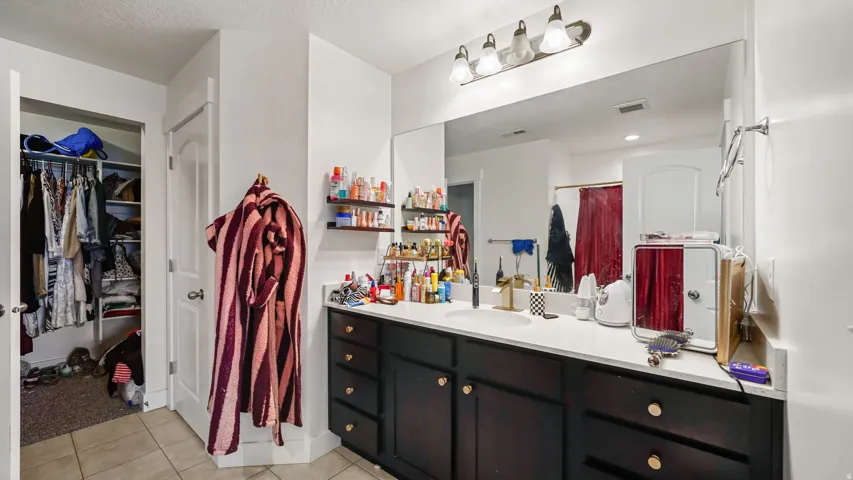Master Bathroom - Vanity with a single basin sink, white countertop, dark wood-finish cabinetry, and a large wall-mounted mirror