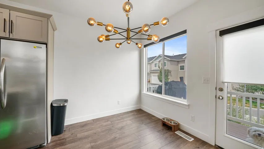 Stainless steel refrigerator, built-in cabinetry, wood-finish flooring, contemporary chandelier, and a glass-paneled exterior door