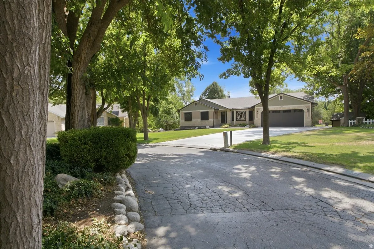Street-level view highlights the home's private circle setting beneath a canopy of mature trees.