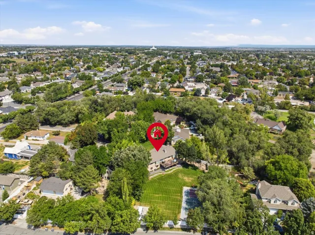 Wide neighborhood aerial showcases the home's established surroundings with mountains in the distance