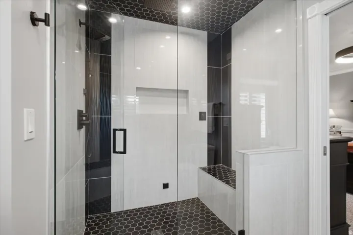 Recently renovated primary bath featuring an impressive glass-enclosed steam shower with built-in seating.