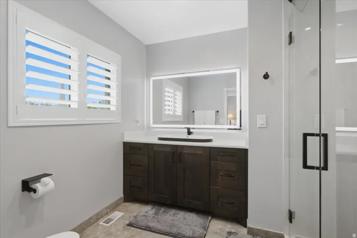 Renovated primary bath combines clean modern finishes with thoughtful storage and an illuminated mirror.