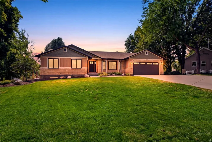 A beautiful first impression at twilight, surrounded by mature trees on a spacious South Jordan lot.