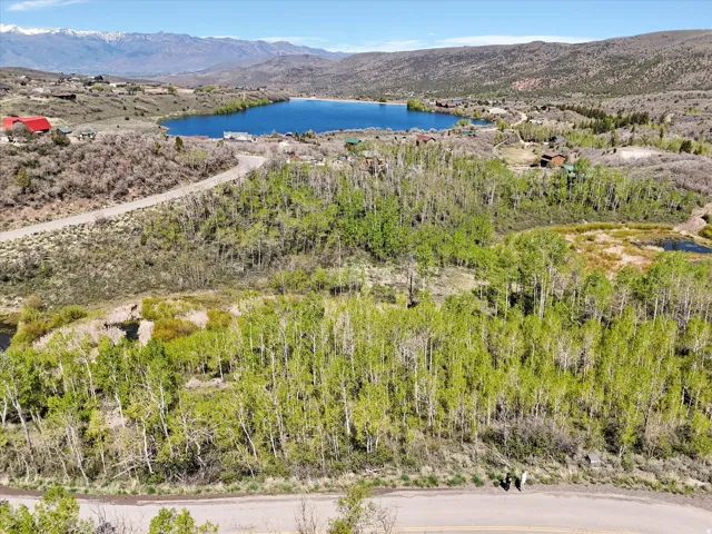 Expansive natural landscape featuring a lake, surrounding hills, and a mountainous backdrop