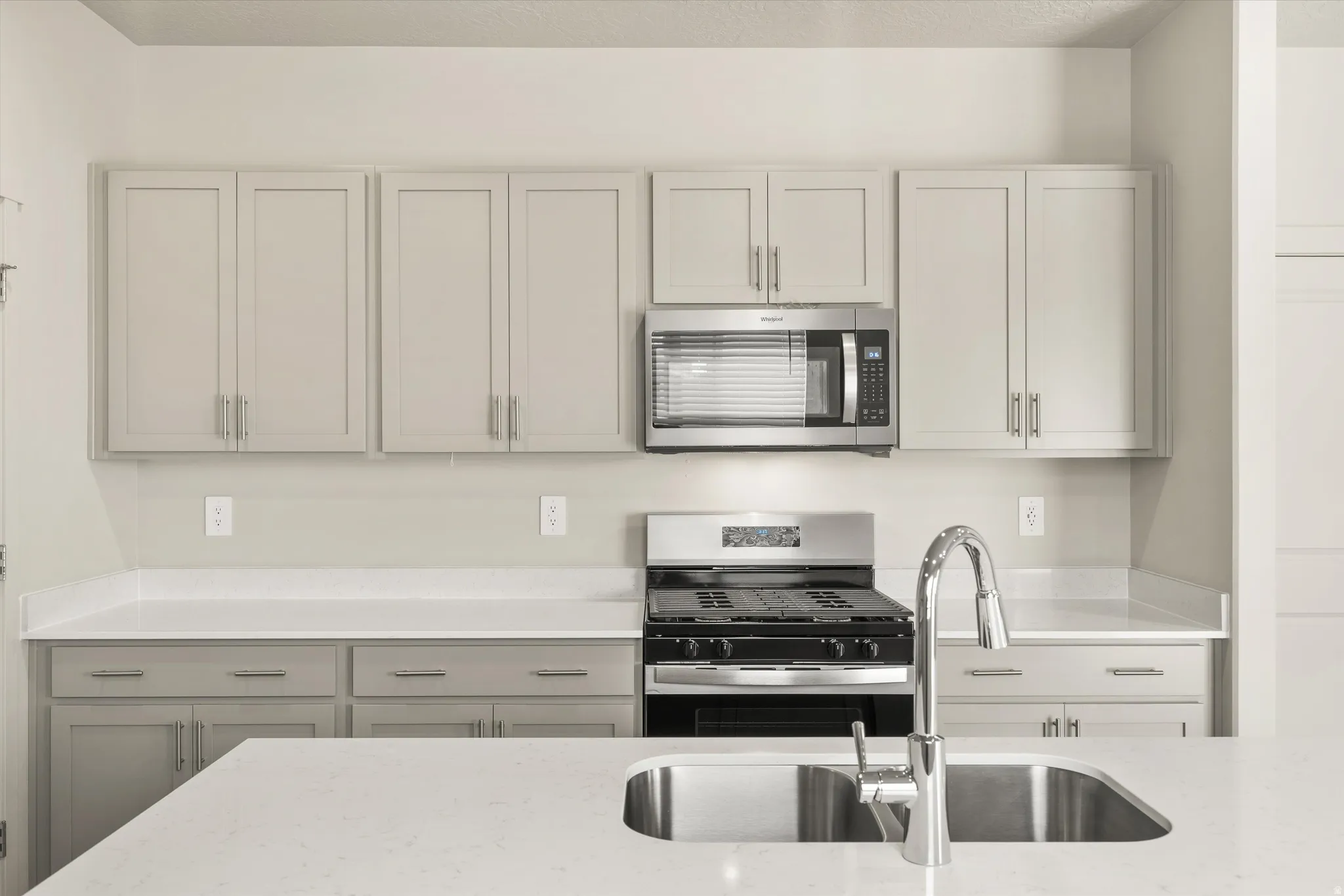 **DISCLAIMER** This floorplan has upgrades not photographed.Stainless steel appliances, light-toned cabinetry, solid surface countertops, kitchen island with an undermount sink, and a high-arc pull-down faucet