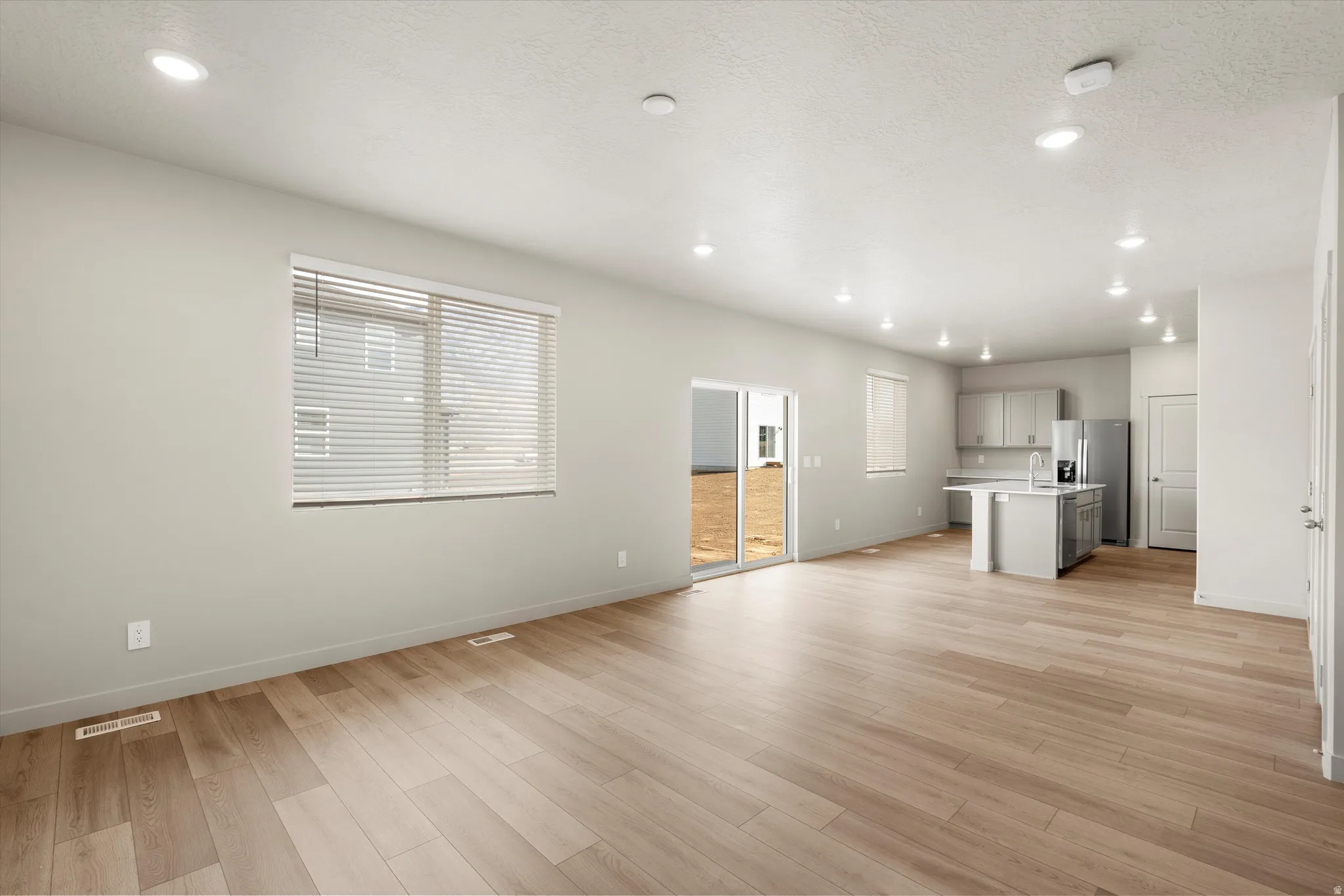 **DISCLAIMER** This floorplan has upgrades not photographed.Open-concept living space featuring wood-finish flooring, recessed lighting, and a sliding glass door