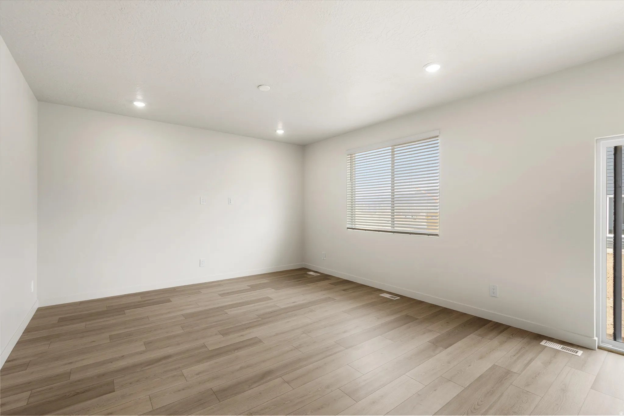 **DISCLAIMER** This floorplan has upgrades not photographed.Recessed lighting, light wood-finish flooring, white walls, window with horizontal blinds, and a sliding glass door