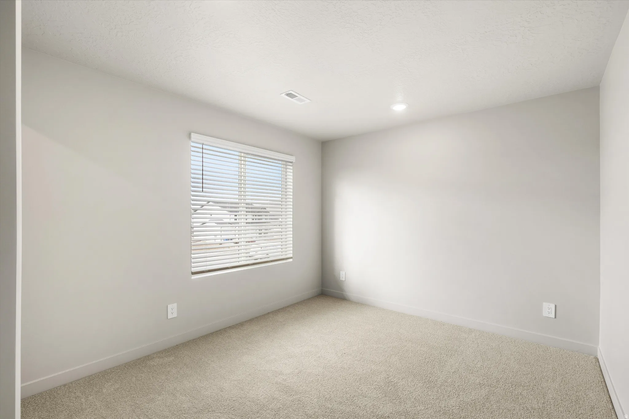 **DISCLAIMER** This floorplan has upgrades not photographed.Neutral-toned carpeted flooring, single window with horizontal blinds, recessed ceiling lighting, and light gray wall paint