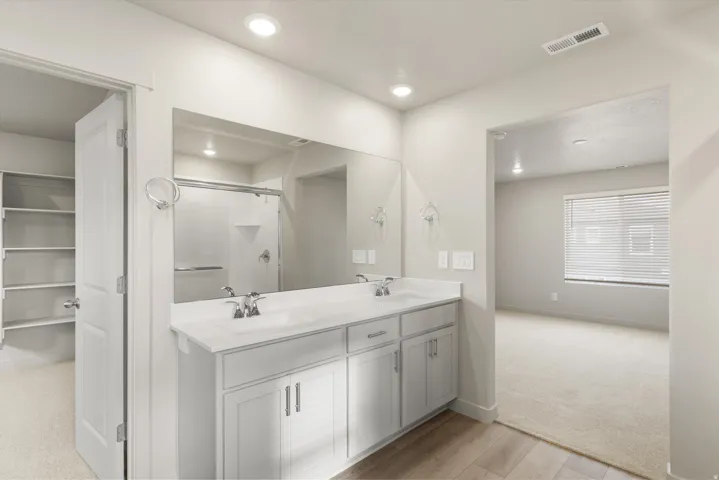 **DISCLAIMER** This floorplan has upgrades not photographed.Double vanity with white cabinetry, polished chrome fixtures, integrated sinks, and a large mirror