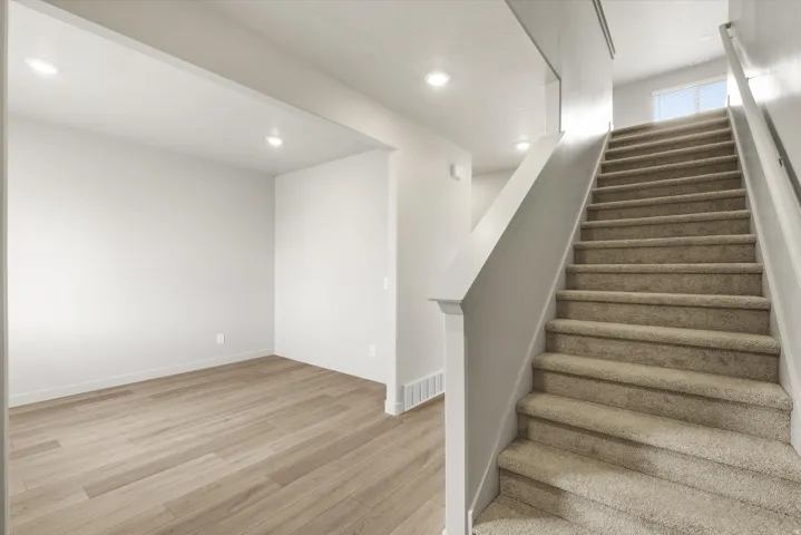 **DISCLAIMER** This floorplan has upgrades not photographed.Carpeted staircase with white balustrade, wood-finish flooring, recessed lighting, and white walls