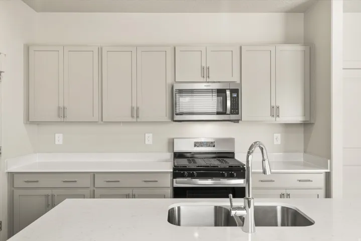 **DISCLAIMER** This floorplan has upgrades not photographed.Stainless steel appliances, light-toned cabinetry, solid surface countertops, kitchen island with an undermount sink, and a high-arc pull-down faucet