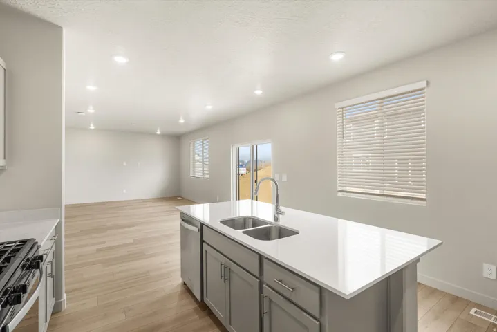 **DISCLAIMER** This floorplan has upgrades not photographed.Spacious kitchen island with a double basin sink, light wood-finish flooring, recessed lighting, and a sliding glass door