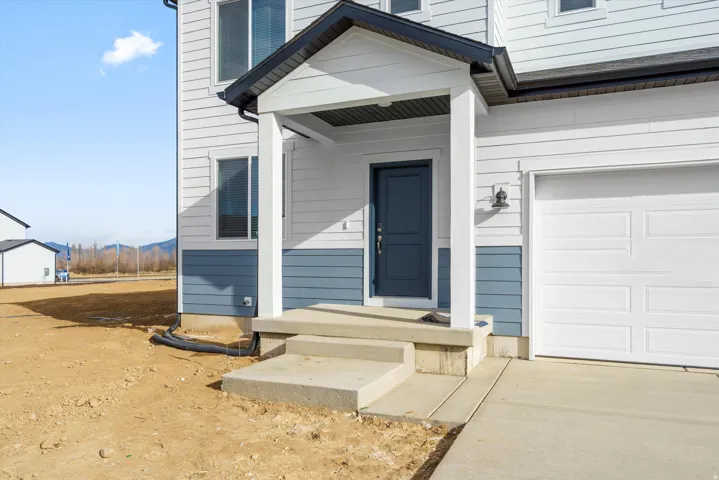 Two-story exterior with horizontal siding, covered entry porch, dark blue entry door, and attached garage with white door