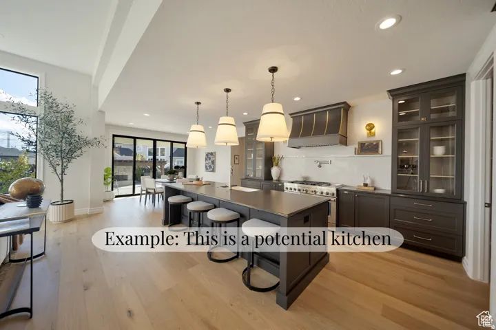 Open-concept kitchen featuring an oversized island with seating, dark wood-finish cabinetry, stainless steel range, and light wood-finish flooring